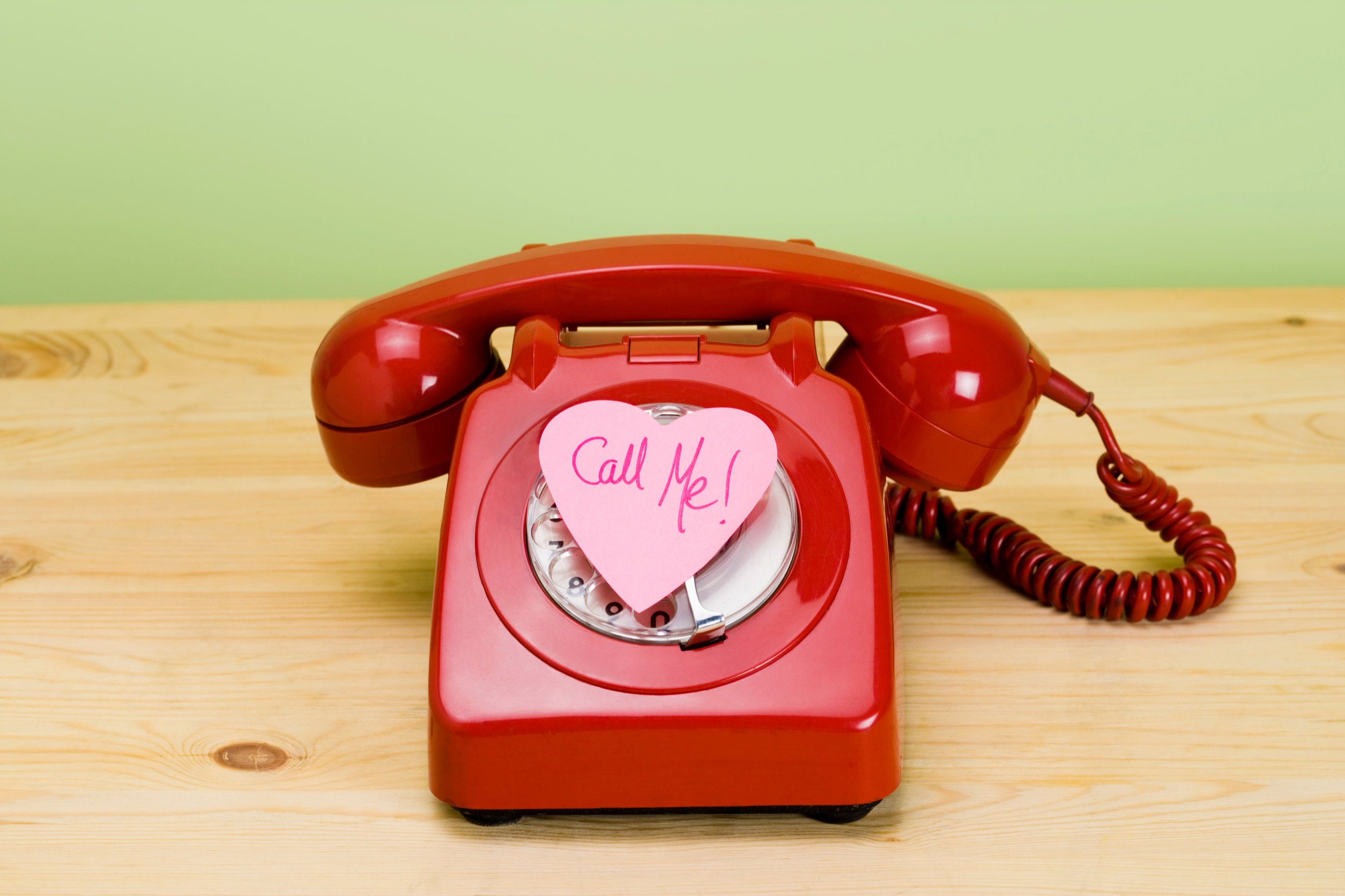 Call me on heart-shaped notepad on telephone
